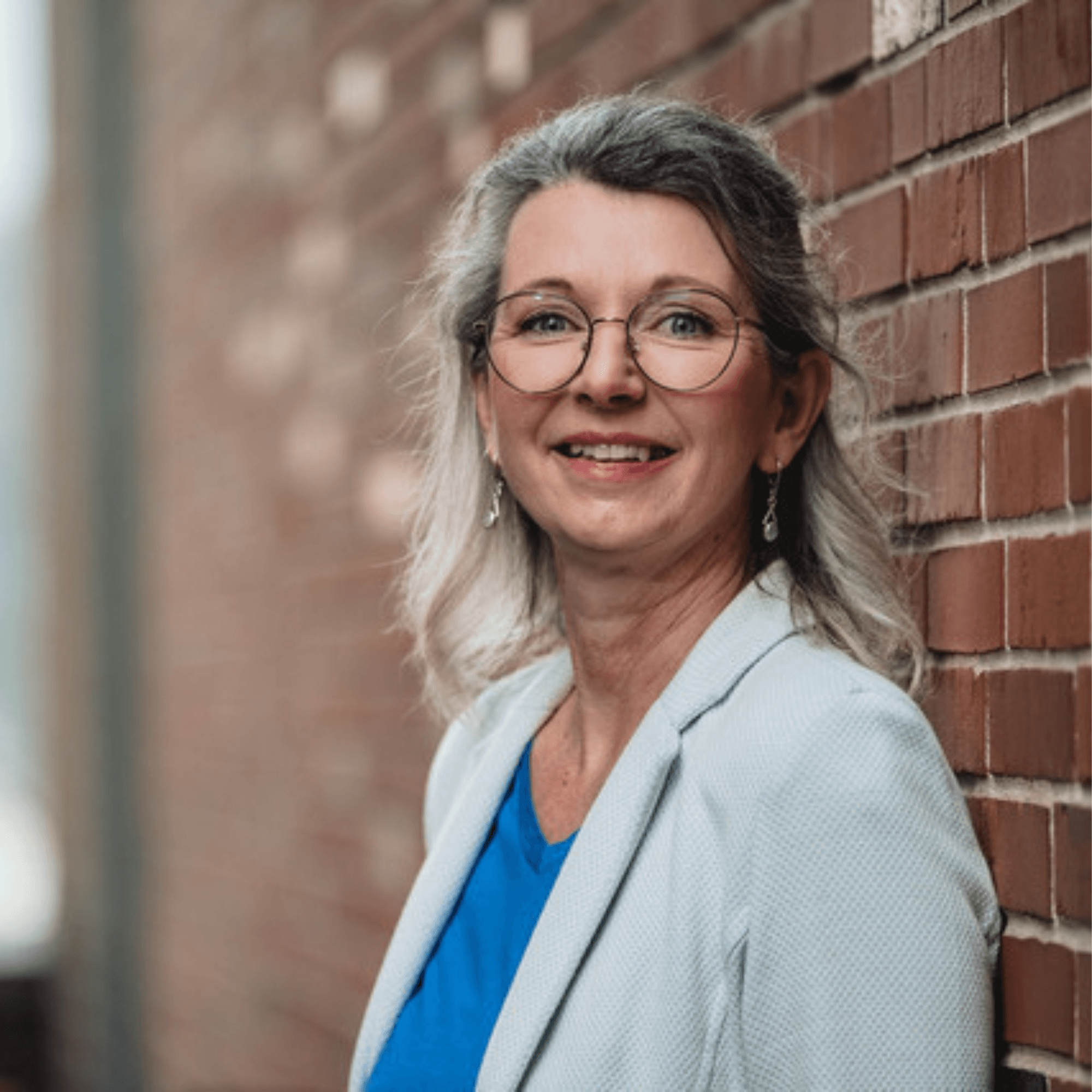 Heike Quendt, Architektin der Zell-Energie, vor der historischen Ziegelwand des Josephs Hofs – Fokus auf Souveränität und Herzenskraft.
