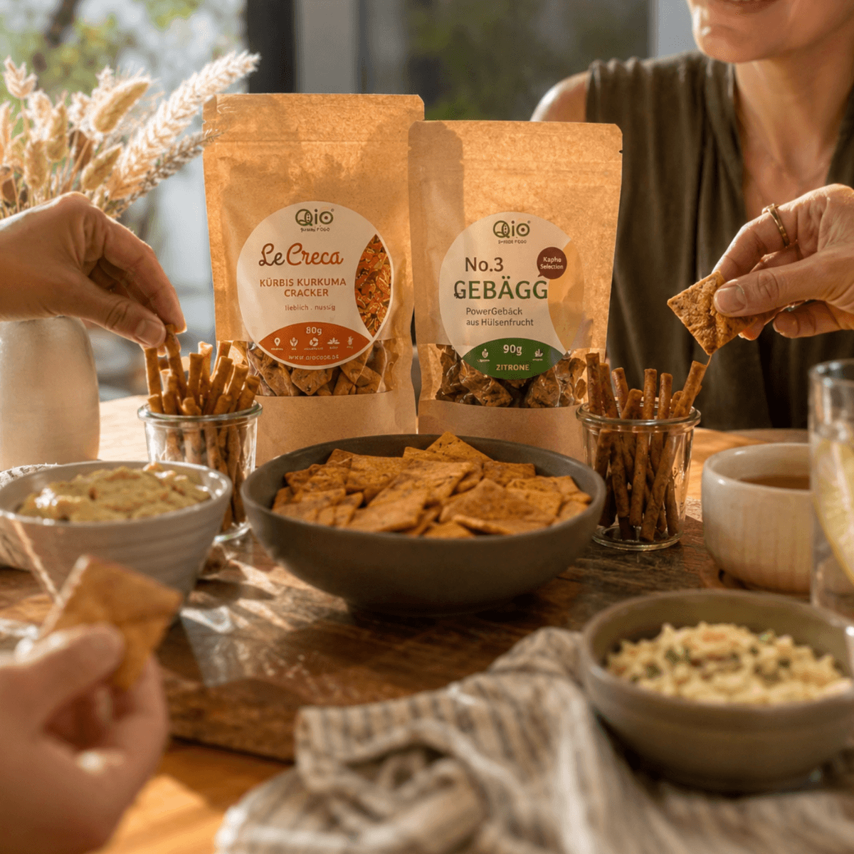 Menschen kommen zusammen und genießen Bio-Snacks von Qio Food in entspannter Atmosphäre.